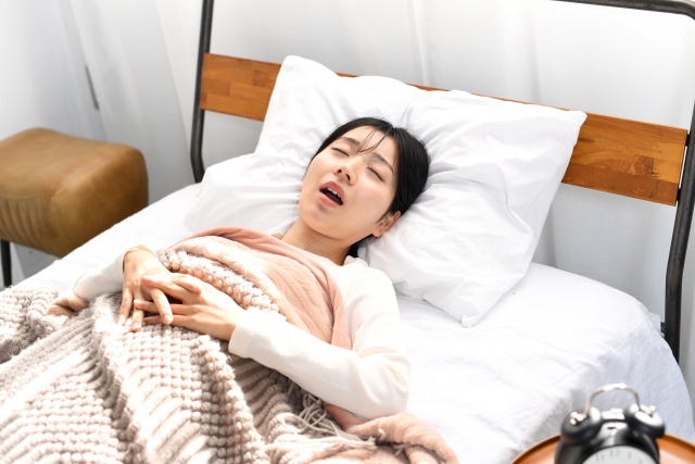 ベッドの上でいびきをかき寝るアジア人女性の画像